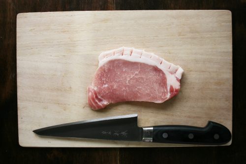 「豚ロースの黒酢はちみつ焼き」の作り方。豚肉の脂部分に切り込みを入れる。