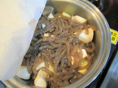 肉じゃがの作り方2。火が通ってきたら★印の調味料を加えてひと混ぜし、その上に他の具材を載せて黒こしょうをしたら、落し蓋をして鍋にもフタをします。